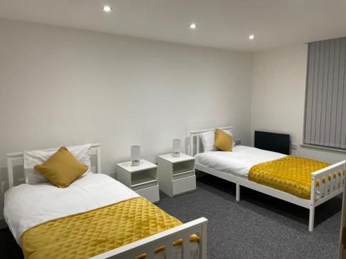 a room with two beds with yellow pillows at Modern - two bed - apartment located in the city of Wolverhampton in Wolverhampton
