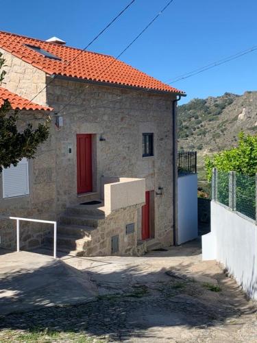 una casa de piedra con puertas rojas y escaleras delante en Casa da Avó Maria, en Monsanto