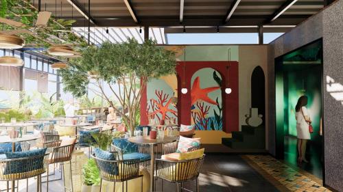 a restaurant with chairs and tables and a painting on the wall at Zone By The Park Gopalpur in Gopālpur