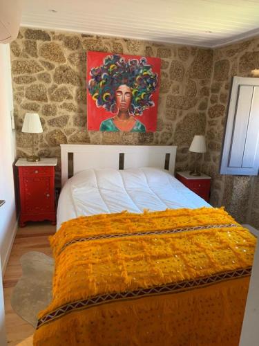 a bedroom with a bed with a painting on the wall at Casa da Avó Maria in Monsanto