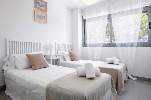 2 camas en una habitación con paredes blancas y ventana en Ático Saona en Aduanas