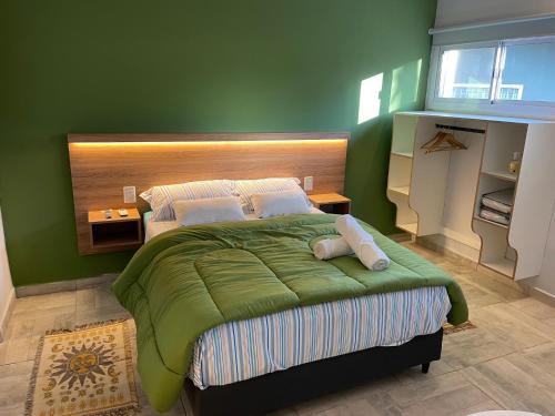 a bedroom with a large bed with a green wall at CasitaLiu in Villa General Belgrano