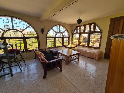 een woonkamer met ramen, een bank en een tafel bij Hidden Valley Backpackers in Iringa