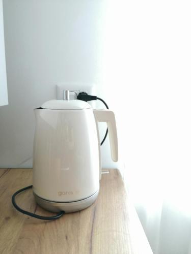 a white slow cooker sitting on a wooden table at Cozy Apartment Bujorilor Suceava in Suceava