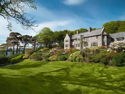 una casa grande con un frondoso patio verde en Ard na Sidhe Country House Hotel en Killorglin
