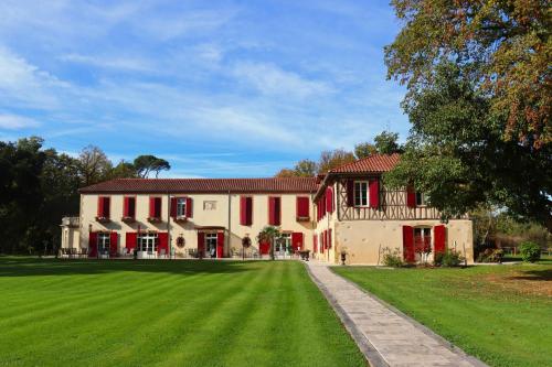 ein großes Haus mit grünem Rasen davor in der Unterkunft Maison D'hôtes Sainte-Marie in Mirande