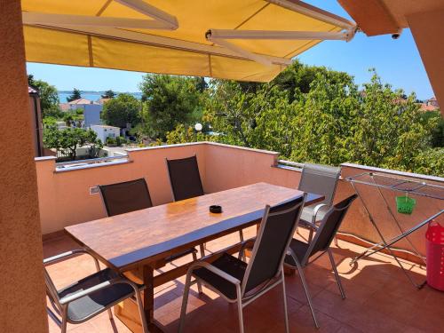 une table et des chaises en bois sur une terrasse avec un parasol dans l'établissement Apartment Leonardo, à Vrsi