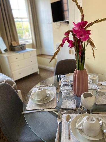 a table with plates and a vase with flowers on it at The Ashton Mews in Bristol