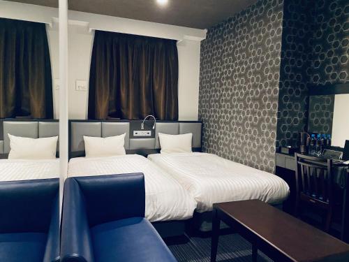 福岡市にあるホテルフラトン福岡博多のベッド2台、テーブル、ソファが備わる客室です。