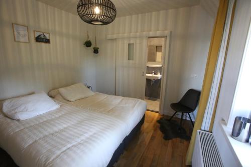 1 dormitorio con 1 cama y 1 silla en Recreatieappartement BoerdeRijlst - De Winkel, en Sint Nicolaasga