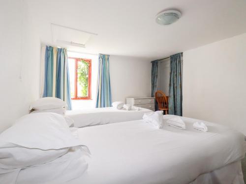 two white beds in a room with blue curtains at Atlantic Farmhouse in Bude