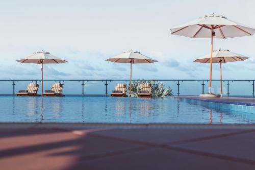 una piscina con sedie e ombrelloni di Aya Sophia Villa Garden Hotel a Dar es Salaam