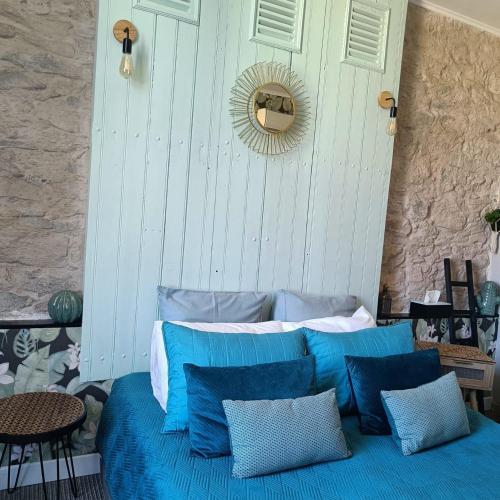 a bed with blue pillows and a mirror on a wall at Entre Bastide et Cité et son rooftop in Carcassonne