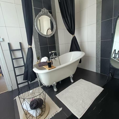 a bathroom with a white tub and a mirror at Entre Bastide et Cité et son rooftop in Carcassonne