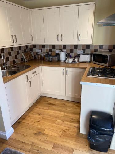 a kitchen with white cabinets and a wooden floor at The Ashton Mews in Bristol