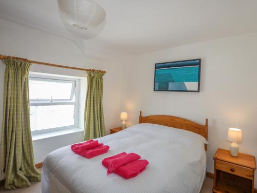 a bedroom with a bed with two red towels on it at Ty Bach - Llanberis in Caernarfon