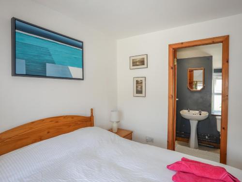 a bedroom with a bed and a sink and a mirror at Ty Bach - Llanberis in Caernarfon