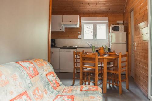 een keuken en eetkamer met een tafel en een koelkast bij Village de Gîtes des Chalets du Camping du Golf in La Canourgue