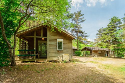 een kleine hut in het bos met een veranda bij Village de Gîtes des Chalets du Camping du Golf in La Canourgue