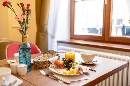 a table with a plate of food and a vase of flowers at Portal House Apartments in Kraków