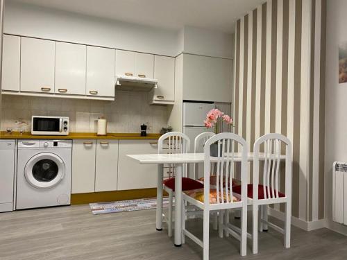 a kitchen with a table and two chairs and a washing machine at Aire de Sanabria Puebla in Puebla de Sanabria