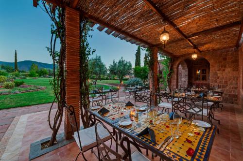 a dining room with tables and chairs on a patio at Kasbah Angour in Tahannout