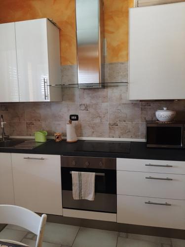 a kitchen with white cabinets and a black counter top at Casa vacanze da Cinzia in Zanica