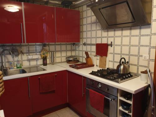 a kitchen with red cabinets and a stove top oven at Appartamento Cà Lio in Venice