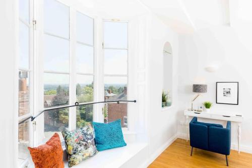 a white room with windows and a bench with pillows at The Old Morgan Period 3 Bed Duplex in Great Malvern