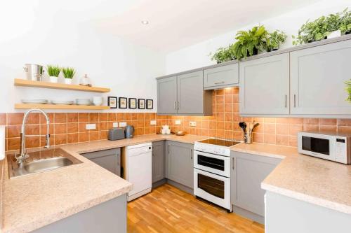 a kitchen with white cabinets and white appliances at The Old Morgan Period 3 Bed Duplex in Great Malvern