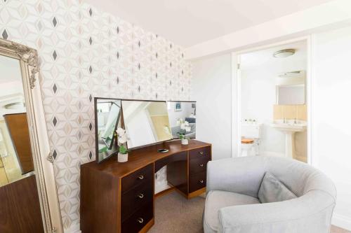1 dormitorio con escritorio, espejo y silla en The Old Morgan Period 3 Bed Duplex, en Great Malvern