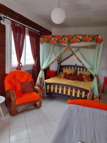 a bedroom with a canopy bed and a chair at Avamada Lodge in Ivato