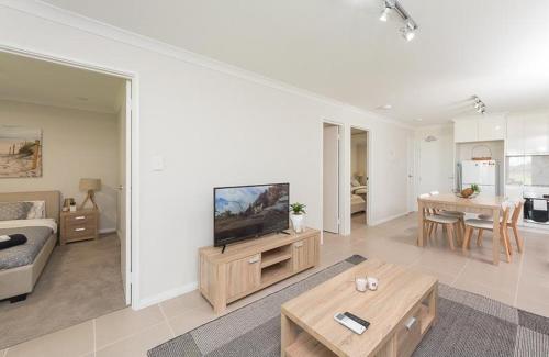 ein Wohnzimmer mit einem TV, einem Sofa und einem Tisch in der Unterkunft Yaran Suites in Rockingham