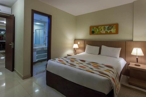 a bedroom with a large bed and a bathroom at The Sun Full Condominiun in Brasília