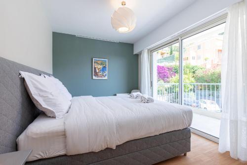 une chambre avec un lit et une grande fenêtre dans l'établissement Amazing Sea View 2Bdr Swimming Pool Parking, à Villefranche-sur-Mer