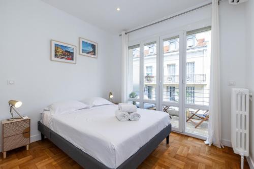 une chambre blanche avec un lit et une grande fenêtre dans l'établissement Quiet 1 Bdr Downtown Terrace AC & Parking, à Nice