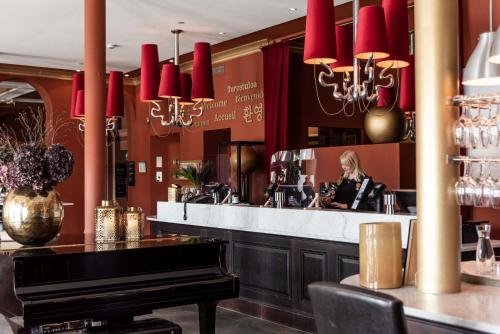 a woman sitting at a bar in a restaurant with a piano at Varbergs Stadshotell & Asia Spa in Varberg