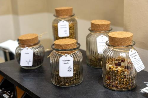 a group of four glass jars filled with spices at Hotel Ancora in Verbania