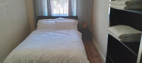 a bedroom with a bed with white sheets and a window at Lovely 1 bedroom apartment with garden in London