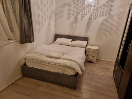 a small bedroom with a bed with white sheets at 2 bedroom flat with balcony London in London