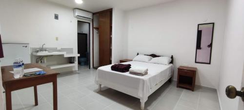 1 dormitorio con cama blanca y lavamanos en Calaveritas Rooms, en Playa del Carmen