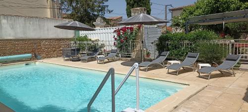 - une piscine avec des chaises longues et des parasols dans l'établissement Lacanepière, à Générac