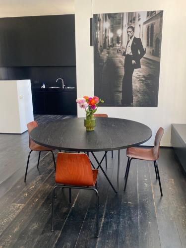 un tavolo nero con sedie e un vaso di fiori sopra di ANNA a Gand