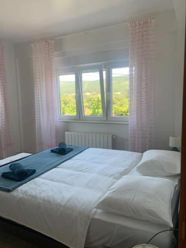 a bedroom with a large white bed with two windows at Casa Frutales - Landhaus mit Garten nahe Strand und Finisterre in Fisterra