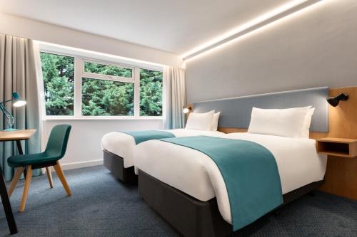 a bedroom with two beds and a desk and a window at Holiday Inn Birmingham Airport - NEC by IHG in Bickenhill