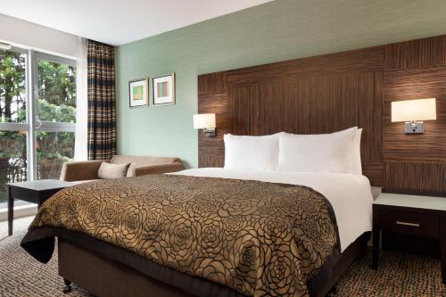 a hotel room with a large bed and a chair at Holiday Inn Birmingham Airport - NEC by IHG in Bickenhill