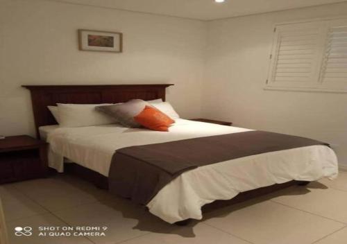 a bedroom with a bed with white sheets and orange pillows at Beacon Rock - 6 sleeper Luxurious Apartment in Durban