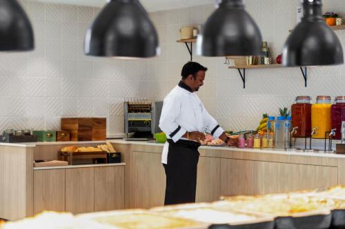 a man standing in a kitchen preparing food at Holiday Inn Birmingham Airport - NEC by IHG in Bickenhill