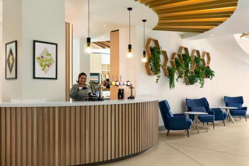 a woman sitting at a bar in a restaurant at Holiday Inn Birmingham Airport - NEC by IHG in Bickenhill