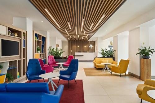 un vestíbulo con mesas y sillas coloridas en Holiday Inn Birmingham Airport - NEC, an IHG Hotel en Bickenhill